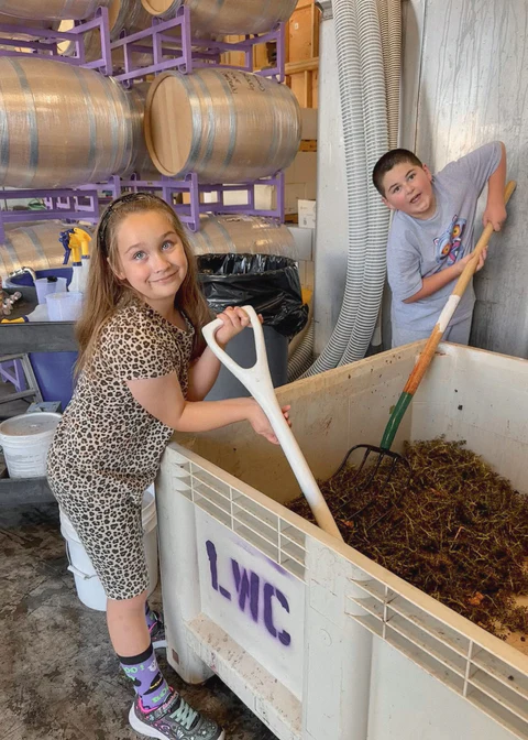 Cooper and River working with grape stems in the winery